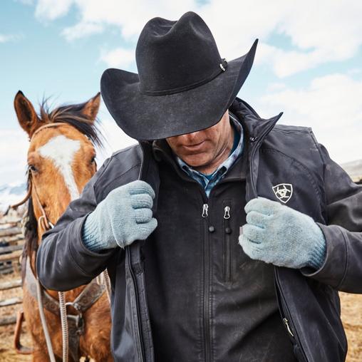 Man in ariat jacket next horse in a cowboy hat